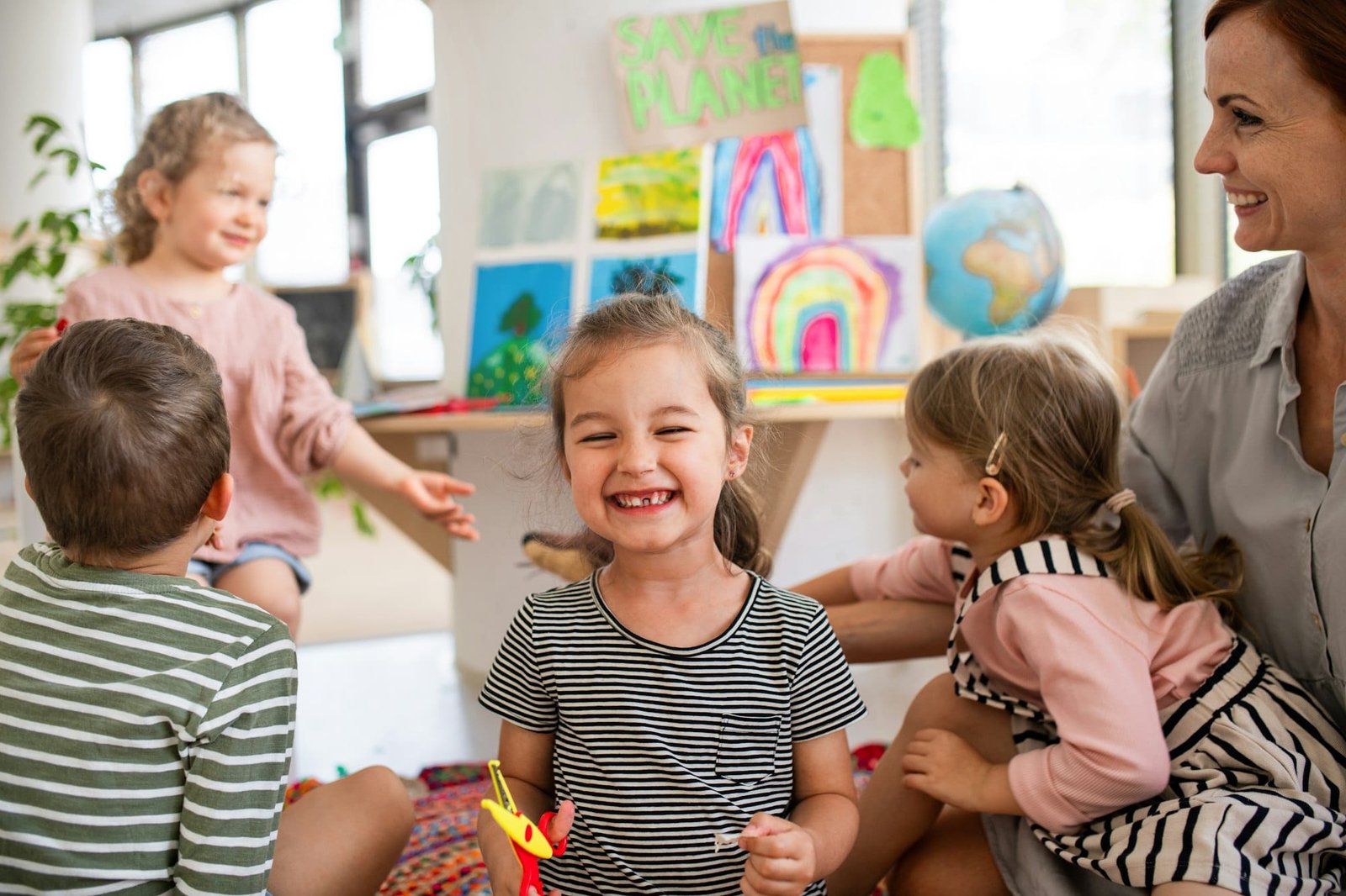 Small girl showing lost baby tooth indoors in classroom, looking at camera
